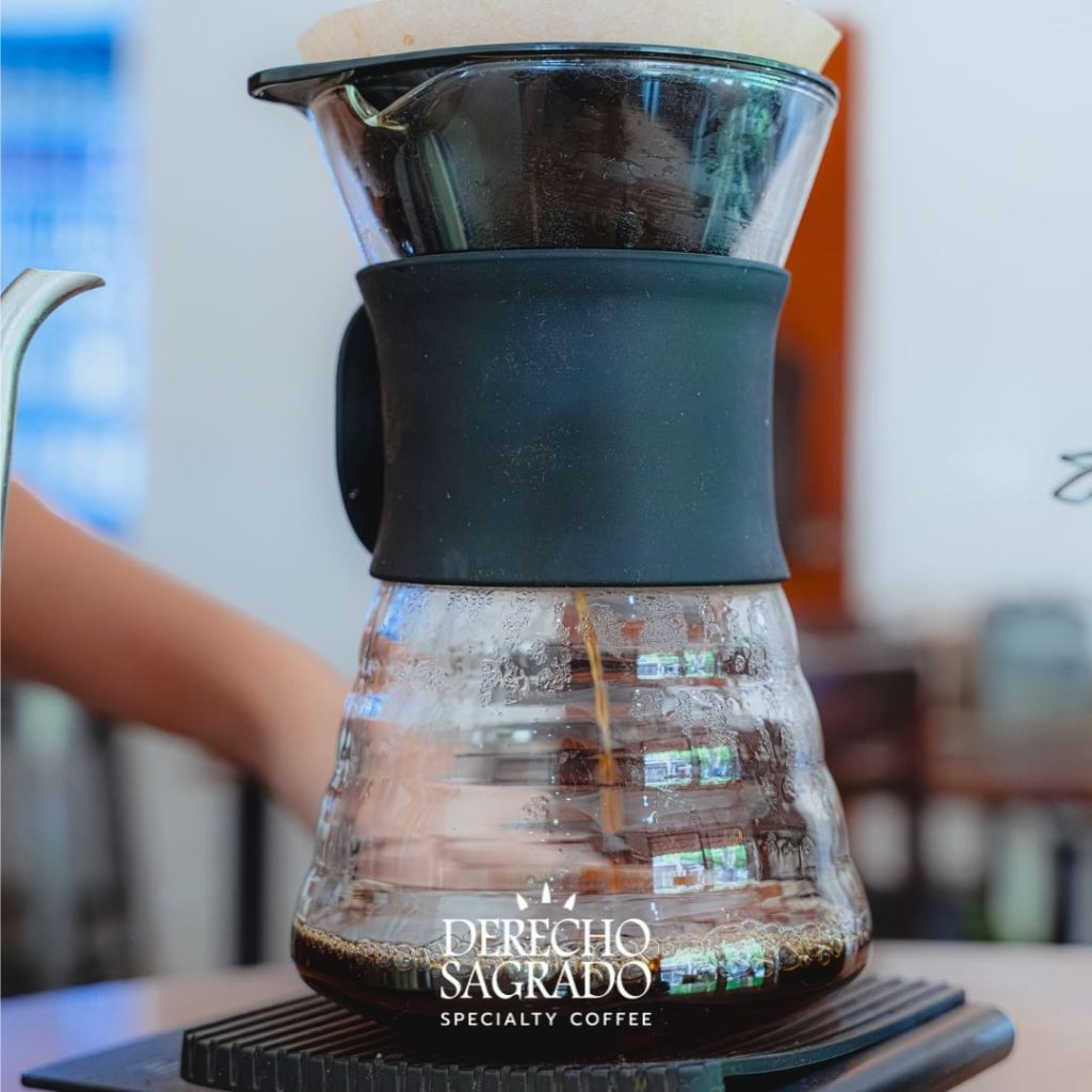 Pour-over coffee setup at Derecho Sagrado featuring a ceramic dripper on top of a glass carafe on a digital scale.